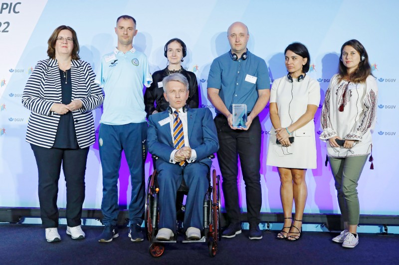v.l.n.r: Kerstin Griese (Parl. Staatssekretärin im BMAS) mit Semenenko Yaroslav, paralympischer Schwimmer, dem Präsidenten des paralympischen Komitees der Ukraine, Valerii Sushkevych sowie der ukrainischen Delegation. (Foto: Jan Röhl / DGUV)